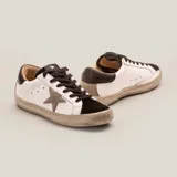 Zapatillas urbanas blancas de cuero vacuno, con puntera y talón en gamuza negra, aplique de estrella en cuero color aluminio y cordones negros encerados.