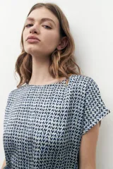 Blusa beige con estampado geométrico, cuello redondo y mangas cortas.