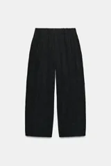 Pantalón fluido de tiro medio color verde militar, con cintura elástica en la parte trasera, pinzas en el delantero y bolsillos laterales ocultos en la costura. Presenta un diseño de pernera ancha y corte tobillero, con cierre frontal de cremallera y botón.