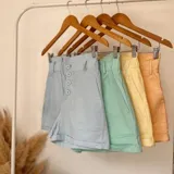 Short color amarillo pastel con cintura elastizada y detalle de botones frontales.