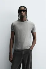 Camiseta gris de corte slim fit, confeccionada en tejido de algodón con elasticidad, cuello redondo y manga corta.