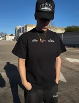 Remera negra de corte oversize con estampado gráfico en la espalda con la inscripción 'New York' en blanco y detalles en rojo, y diseño frontal minimalista.
