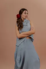 Pollera larga de lino color gris topo, de diseño amplio con volumen, movimiento y bolsillos delanteros. Cuenta con elástico en la cintura y detalles de pinzas y sobretelas en los laterales.