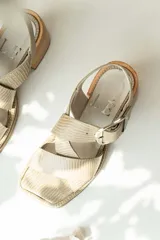Sandalias de cuero negro con textura de reptil, diseño de punta cuadrada y taco bloque de madera. Presentan tiras cruzadas en el empeine y una hebilla metálica grande decorativa.