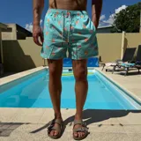 Short de baño negro con estampado de rodajas de naranja, cintura elástica con cordón ajustable y logo circular en el ruedo.