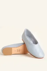 Chatitas de cuero color celeste, con borde superior fruncido y detalle trenzado. Suela plana de cuero con taco bajo.
