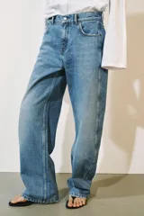Jeans de tiro medio confeccionados en denim con efecto lavado, diseño de pernera curva y corte recto. Cuenta con cinco bolsillos, trabillas en la cintura y cierre frontal con cremallera y botón metálico.