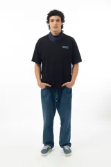 Remera negra de algodón con estampado en la espalda de cuatro retratos con diferentes cortes de pelo y logos de marcas deportivas.