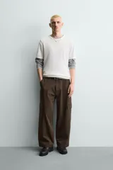 Pantalón cargo de corte relajado confeccionado en tejido de algodón con elasticidad. Presenta bolsillos laterales tipo cargo con solapa en las perneras, bolsillos frontales y bolsillos traseros de doble vivo. Cierre frontal con cremallera y botón.