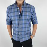 Camisa de manga corta con cuello italiano, a cuadros grandes en tonos grises y celestes. Tiene un logo bordado en el pecho. Confeccionada en algodón 100%.