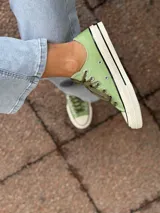 Zapatillas bajas de lona color blanco, con cordones marrones, puntera de goma y base blanca.