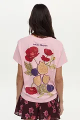 Remera de algodón color rosado, de manga corta, con cuello redondo y detalle de estampa y bordado frontal con diseño de una flor y una higuera.