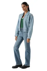 Campera de jean de corte corto con cierre frontal, cuello clásico y cintura elástica. Presenta mangas largas con puños abotonados y costuras tipo western en el pecho.