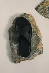 Pantalón negro de tejido suave con corte relajado, cintura elástica con cordón oculto y pliegues frontales. Presenta bolsillos laterales y bolsillos traseros ribeteados.