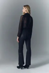 Pantalón de jean tiro medio, calce ajustado, con proceso de coating de acabado símil cuero y pierna levemente acampanada.