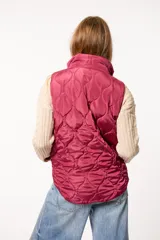 Chaleco puffer color borgoña con diseño capitoneado, cierre frontal con cremallera y botones a presión, y dos bolsillos laterales.