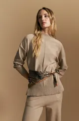 Polera de tejido de punto color beige, con cuello alto, mangas largas y diseño holgado. Presenta un detalle de costura vertical en el frente y un acabado acanalado en la parte inferior.