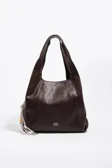 Bolso de mano y hombro grande de cuero marrón oscuro, tipo hobo, con diseño estructurado mediante costuras frontales y asa integrada. Incluye detalle lateral de cordones blancos con cuentas decorativas y el logotipo plateado de la marca en la parte inferior frontal.