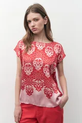 Blusa de satén con estampado floral bicolor en tonos rojo y rosado, de corte recto, cuello redondo y mangas cortas.