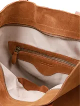 Cartera tote de gamuza color marrón maíz, con asas largas de cuero liso en tono tostado y placa con el logo de la marca en el frente.