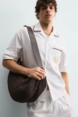 Bolso de hombro de diseño trenzado color marrón, con compartimento principal con cierre de cremallera, bolsillo plano interior y asa de hombro ajustable.