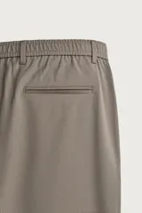 Pantalón de corte slim fit y color negro, confeccionado en tejido elástico. Cuenta con cintura elástica, trabillas, bolsillos frontales y cierre con cremallera y botón.