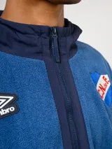 Campera de polar blanca con capucha y detalles en azul marino, con cierre frontal completo. Presenta el logo de Umbro y el escudo del Club Nacional de Football en el pecho.