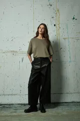 Pantalón de cuero sintético negro de corte ancho y tiro alto, con costuras verticales decorativas en el frente y cierre frontal con botón.