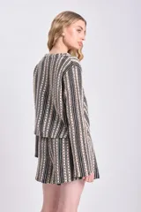 Top de punto crochet con diseño de rayas verticales en negro y beige, cuello redondo y textura calada con motivos florales.