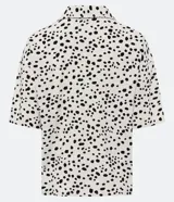 Camisa de manga corta en tejido de viscolino con estampado de lunares irregulares, cuello camisero en pico y abotonado frontal.