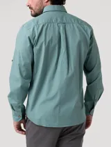 Camisa de manga larga color verde menta, confeccionada en popelina 100% algodón orgánico. Presenta cuello camisero, botones de madera, un bolsillo de parche en el pecho con logo bordado y presillas con botón en las mangas para sujetarlas enrolladas.