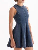 Vestido corto de denim azul con gran elasticidad, sin mangas y cuello redondo. La parte superior es ajustada y la falda tiene vuelo. Presenta un lavado irregular con efecto desgastado.
