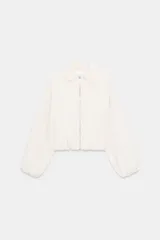 Chaqueta de corte corto y diseño abullonado en color marrón oscuro, con cuello solapa, mangas largas con puños elásticos y cierre frontal con cremallera metálica. Cuenta con bolsillos delanteros de doble vivo.
