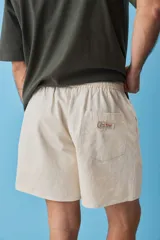Short de gabardina color beige con calce relajado, cintura elástica con cordón ajustable y largo a mitad de muslo.