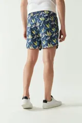 Short de baño con estampado botánico en tonos turquesa, blanco y azul. Presenta cintura elástica con cordón ajustable, dos bolsillos laterales y uno trasero, además de un logo bordado en la pierna.