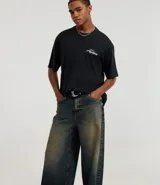 Pantalón de jean con corte baggy, de tiro alto y pierna ancha. Presenta un diseño de estilo vintage con acabado desgastado y trabillas en la cintura.