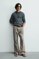 Pantalón de pana de corte flare, color verde oliva desgastado, con cinco bolsillos y cierre frontal de cremallera y botón.