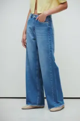 Pantalón de jean azul de tiro medio/bajo, con calce extra relaxed y piernas anchas. Confeccionado en denim rígido liviano, con lavado acid wash azul y desflecado en ruedos.
