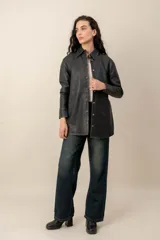 Camisa de cuero negro con efecto lavado, cuello camisero, cierre frontal con broches metálicos y mangas largas.