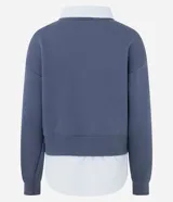 Buzo azul de corte amplio confeccionado en mezcla de algodón y poliéster, con diseño superpuesto que incluye cuello clásico y dobladillo en tono contrastante simulando una camisa por debajo.