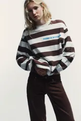 Camiseta de manga larga con cuello redondo y estampado de rayas horizontales en blanco y marrón. Incluye texto azul "TRIBECA MIDTOWN" estampado en el pecho.