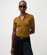 Blusa polo de punto color mostaza, con manga corta, cuello camisero y cierre frontal de cremallera.