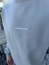 Buzo de algodón con calce oversize, cuello redondo y puños acanalados. Presenta un bordado minimalista con el logo de la marca en el centro del pecho.