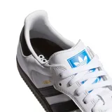 Championes Adidas modelo Samba ADV, de diseño clásico con base blanca, tres rayas laterales negras, puntera de gamuza gris y suela de goma color caramelo.
