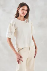 Remera negra de algodón con mangas tres cuartos abullonadas y detalle de bordado calado tipo ojal en la zona del antebrazo.