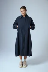 Trench midi color negro, confeccionado en mezcla de algodón y nylon con acabado repelente al agua. Presenta diseño con tajos laterales, bolsillos internos y etiqueta de marca en la espalda.