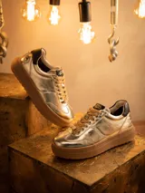 Championes de cuero metalizado en color dorado, con diseño inspirado en C-3PO. Presentan cordones al tono, suela de goma tipo plataforma en color marrón y detalles de marca Star Wars en la lengüeta y el frente.