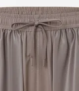 Bermuda deportiva gris con cintura elástica, cordón de ajuste, bolsillos con cremallera, recorte lateral con agujeritos y abertura en el bajo.