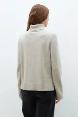 Sweater beige melange de cuello alto, tejido de punto liso y corte clásico.