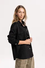 Sobrecamisa oversize de efecto gamuza en color marrón, con cierre frontal de botones metálicos, cuello clásico y bolsillos frontales.